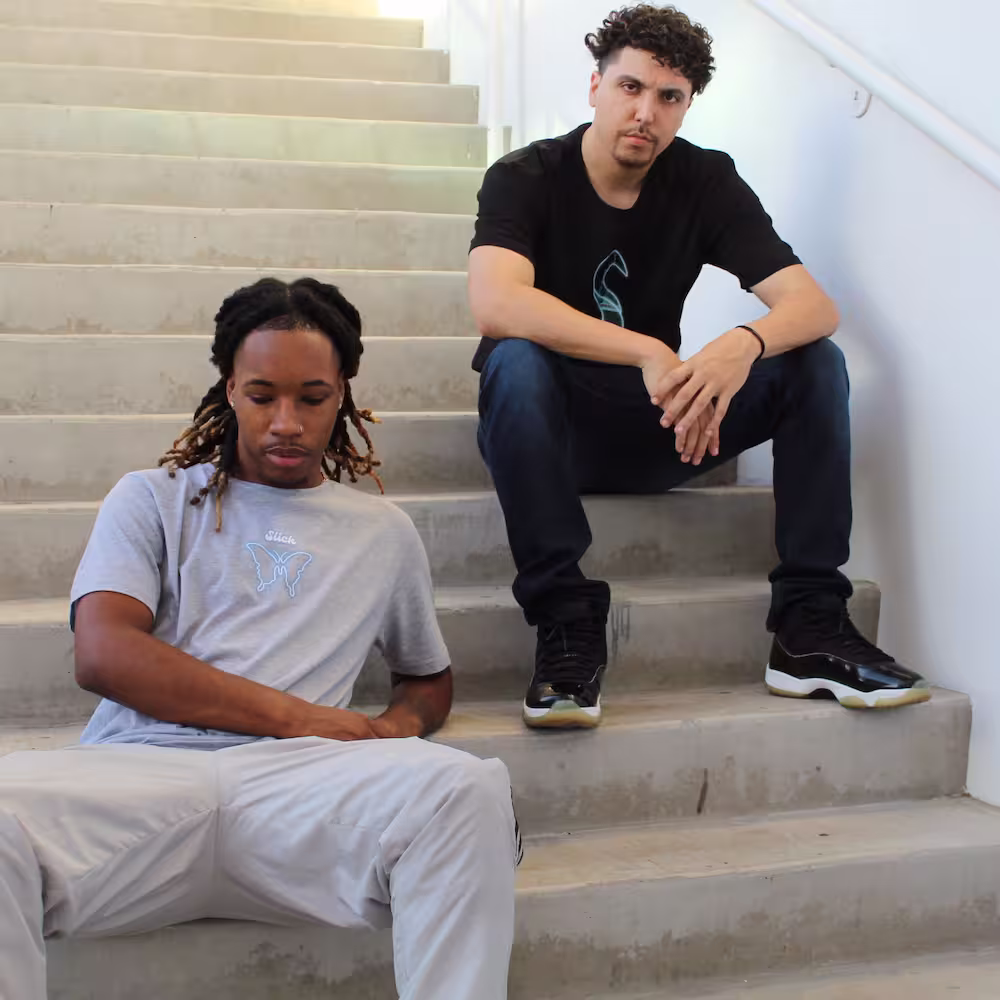 Electric Wings Shirts on 2 models sitting on some steps showing off the gray and black shirts